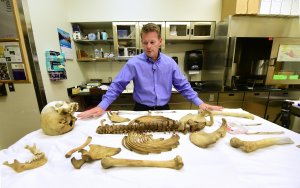 Pima County medical examiner Dr. Gregory Hess stands over a table with the laid out skeletal remains of a person who died trying to cross the US-Mexico border at the medical examiner's office in Tucson on Oct. 13, 2016. (Credit: Frederic J. Brown/AFP/Getty Images)