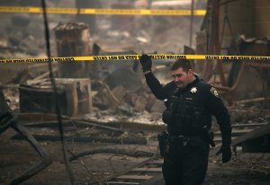 A Paradise police officer walks under crime scene tape that blocks off an area where human remains were found in a car that was destroyed by the Camp Fire on Nov. 15, 2018, in Paradise. (Credit: Justin Sullivan / Getty Images)