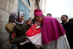 Latin Patriarch of Jerusalem Pierbattista Pizzaballa greets a Muslim Palestinian woman and a baby in the West Bank city of Bethlehem, on Dec. 24, 2018. (Credit: HAZEM BADER/AFP/Getty Images)