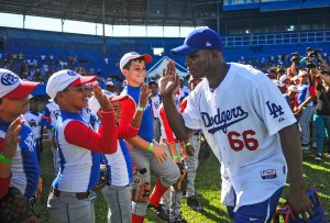 Cuban MLB player Yasiel Puig high fives Cuban children at the Latin American Stadium in Havana on Dec. 16, 2015. (Credit: Yamil Lage / AFP / Getty Images)