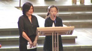 Mai, the wife of late KTLA anchor and reporter Chris Burrous, stands alongside their daughter, 9-year-old Isabella, as she addresses mourners during a memorial service in Whittier on Jan. 11, 2019. (Credit: KTLA)