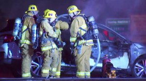 Los Angeles Fire Department officers at the scene where a vehicle was charred black after catching fire on the 101 Freeway on Jan. 28, 2019.