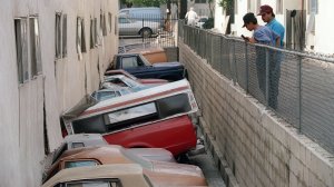 Two men inspect damage to cars and apartment complex after Northridge earthquake, on January 21, 1994, in Canoga. (Credit: A. CLARY/AFP/Getty Images)