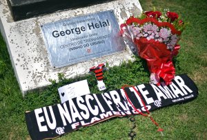 A sign reading "I was born to love you Flamengo" and flowers are seen by a plaque at the entrance of Brazilian football club Flamengo training center, in Rio de Janeiro on Feb. 8, 2019, after a deadly fire. (Credit: Carl De Souza / AFP / Getty Images)