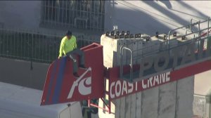A person is seen sitting atop a crane in Koreatown. (Credit: KTLA)
