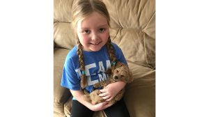 Emma Mertens, a 7-year-old dog lover fighting cancer, poses with a pup. The Wisconsin native has received more than 80,000 pictures of dogs along with letters from around the world. (Credit: Geoff Mertens via CNN)