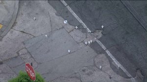 Police evidence markers sit at the corner of 63rd and Hoover streets in South Los Angeles following a shooting that left a woman dead and a 10-year-old girl wounded. (Credit: KTLA)