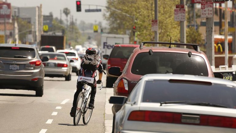 A cyclist rides next to a lane of parked cars on Manchester Avenue in South Los Angeles, one of the deadliest streets in the city for pedestrians and cyclists. Upgrades to Manchester were among hundreds made during the first 3½ years of Vision Zero, an initiative by Mayor Eric Garcetti to eliminate traffic deaths on L.A. streets by 2025. But rather than decline, fatal car crashes have risen 32% since 2015, the year Vision Zero began. In that time, more people have died in traffic collisions — 932 — than were shot to death in the city, according to coroner’s data. (Credit: Al Seib / Los Angeles Times)