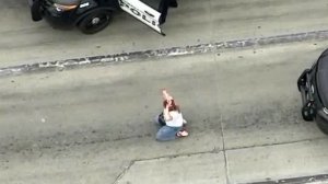 A woman, later identified by police as Alison Hart of Redondo Beach, surrenders to authorities following a pursuit that ended in a shootout in Vernon on May 10, 2019. (Credit: Sky5)