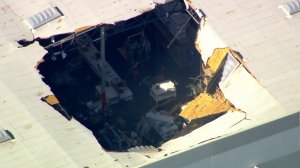 A large is is visible in the roof of a building after an F-16 pilot ejected just before a crash near March Air Reserve Base in Riverside County on May 16, 2019. (Credit: KTLA)