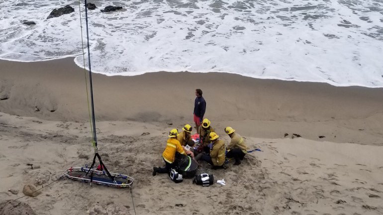 Firefighters treat a man who was injured in a crash landing in a hang glider along Pacific Coast Highway in Ventura County, near the Los Angels County line, on May 26, 2019. (Credit: Ventura County Fire Department)