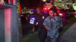 Police detain a bloodied man in handcuffs after he allegedly fatally stabbed his wife with a machete and injured three neighbors who came to her defense on June 22, 2019. (Credit: RMG News)