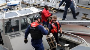 Crew members from the U.S. Coast Guard Cutter Monro transfer packages of cocaine from an interceptor boat to the cutter following an interdiction in the Eastern Pacific Ocean on June 6, 2019. (Credit: USCG)