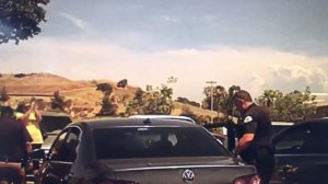 A bystander claps as police remove a Dachshund from a car in a West Covina parking lot as temperatures neared 100 degrees on July 25, 2019. (Credit: West Covina Police Department)