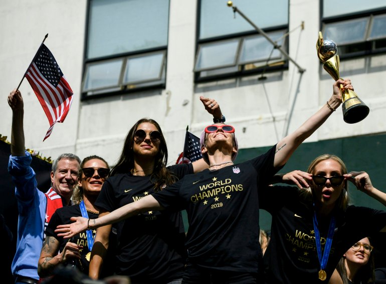 Megan Rapinoe (C), NY Mayor Bill de Blasio (L) and other members of the World Cup-winning US women's team take part in a ticker tape parade for the women's World Cup champions on July 10, 2019, in New York. (Credit: JOHANNES EISELE/AFP/Getty Images)