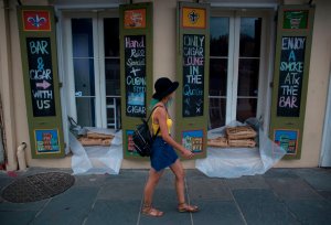 A woman walks past a cigar lounge and bar lined with sandbags in New Orlean's French Quarter ahead of the arrival of Tropical Storm Barry on July 11, 2019. (Credit: Seth Herald / AFP / Getty Images)