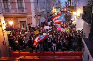 Protesters demonstrate against Ricardo Rossello, the governor of Puerto Rico, near where police are manning a barricade set up along a street leading to the governor's mansion on July 20, 2019, in Old San Juan, Puerto Rico. There have been calls for the governor to step down after it was revealed that he and top aides were part of a private chat group that contained misogynistic and homophobic messages. (Credit: Joe Raedle/Getty Images)