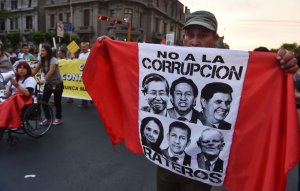 A man carries a flag with the faces of former Peruvian presidents Alberto Fujimori, Alejandro Toledo and Alan Garcia, former first lady Nadine Heredia and her husband, former president Ollanta Humala, and current President Pedro Pablo Kuczynski, while thousands march against corruption through the streets of downtown Lima, Peru on Feb. 16, 2017. (Credit: CRIS BOURONCLE/AFP/Getty Images)