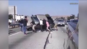 Good Samaritans work to flip an overturned SUV with two people trapped inside following a crash on the 60 Freeway in Montebello on July 7, 2019. (Credit: Maria Mora)