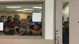 Someone holds up a sign in an overcrowded cell at the Border Patrol's station in McAllen, Texas, this photo from the Office of Inspector General shows.