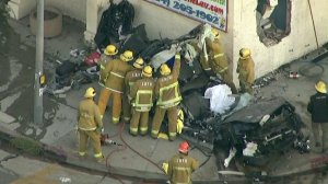 Firefighters investigate the wreckage of a car that was demolished, killing the driver, after the vehicle crashed into a building in the Pico-Robertson area on Aug. 29, 2019. (Credit: KTLA)