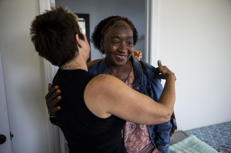 Patricia Wilson gets a hug from Heidi Roberts, left, as she and other tenants move into their new home along Wall Street in April 2018 in Los Angeles. (Credit: Kent Nishimura / Los Angeles Times)