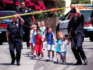 Children from the Jewish Community Center in Granada Hills are escorted to safety by LAPD officers on Aug. 10, 1999. (Credit: Myung J. Chun/Los Angeles Times)