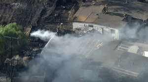 Firefighters work to defend homes after a brush fire ignited in Moreno Valley on Aug. 15, 2019. (Credit: KTLA)