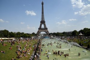 People cool off and sunbathe by the Trocadero Fountains next to the Eiffel Tower in Paris, on July 25, 2019 as a new heatwave hits the French capital. (Credit: BERTRAND GUAY/AFP/Getty Images)