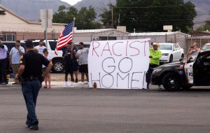 Protestors holding placards are seen as the motorcade carrying Donald Trump passes by on its way to El Paso International Airport in El Paso, Texas, August 7, 2019, following his visit after last weekend's mass shootings. (Credit: SAUL LOEB/AFP/Getty Images)