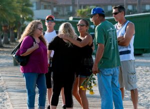 People embrace beside a memorial wall near the Truth Aquatics moorings where the boat that burned and sank off the Santa Cruz islands early in the morning, was based in Santa Barbara, Sept. 2, 2019. (Credit: MARK RALSTON/AFP/Getty Images)