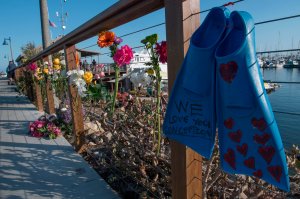 A pair of diving fins and flowers at a memorial wall were placed near the Truth Aquatics moorings in Santa Barbara on Sept. 2, 2019. (Credit: MARK RALSTON/AFP/Getty Images)