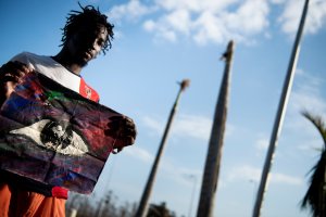 Shaquille Joseph poses with a painting that he made of the eye of Hurricane Dorian while waiting at Marsh Harbor International Airport for evacuation after Hurricane Dorian Sept. 7, 2019, in Marsh Harbor, Great Abaco. - He made the painting of the eye because he was able to escape flood waters and get to his roof during the stillness of the hurricane's eye. Bahamians who lost everything in the devastating passage of Hurricane Dorian were scrambling that same day to escape the worst-hit islands by sea or by air, after the historically powerful storm left at least 43 people dead with officials fearing a "significantly" higher toll. (Credit: BRENDAN SMIALOWSKI/AFP/Getty Images)