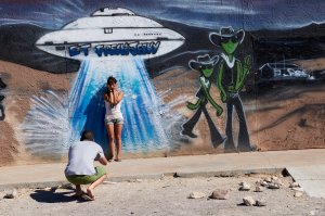 Visitors take photos in front of a mural depicting aliens and a spaceship outside ET Fresh Jerky in Hiko, Nevada, on Sept. 13, 2019. (Credit: Bridget Bennett / AFP / Getty Images)