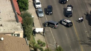 Officers cover the body of a suspect who was fatally shot by police in Van Nuys on Oct. 16, 2019. (Credit: KTLA)