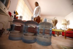 Ruben Mendez stands with water jugs in his home, located about a mile east of the March Air Reserve Base in Riverside County, in 2019. “We thought we had nice, clean water,” he said.(Credit: Genaro Molina / Los Angeles Times)