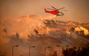 A helicopter drops water to help fight flames during the Saddleridge Fire in Porter Ranch on Oct. 11, 2019.(Credit: Josh Edelson/AFP via Getty Images)