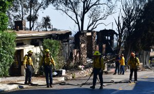 Firefighters gather their hoses near destroyed homes along North Tigertail Road during the Getty Fire on Oct. 29, 2019. (Credit: FREDERIC J. BROWN/AFP via Getty Images)