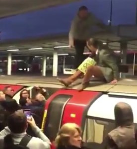 Angry commuters drag an Extinction Rebellion protester off the top of a train in London on Oct. 17, 2019. (Credit: @captheadboard/Twitter)