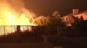 Flames burn dangerously close to a home in Porter Ranch on Oct. 11, 2019. (Credit: KTLA)