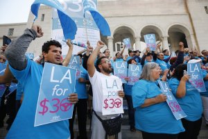 Uber driver Joel Carbonell, left, and Lyft driver Eduardo Belalcazar, center, cheer outside Los Angeles City Hall on Oct. 15, 2019 after lawmakers agreed to study a minimum hourly wage for drivers.(Credit: Al Seib / Los Angeles Times)