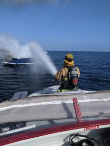 A Harbor Patrol first responder in Orange County hoses down a boat fire 10 miles off the Newport Coast on Oct. 18, 2019. (Credit: Orange County Sheriff's Department)