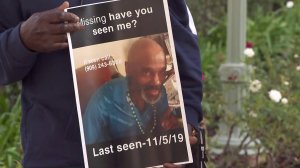 A family member holds a flyer showing Douglas James, who's been missing since being dropped off in the West Carson area by California Highway Patrol on Nov. 5, during a press conference on Nov. 21, 2019. (Credit: KTLA)