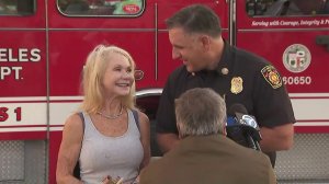 Patty Shales and Jaime Moore, assistant chief at the Los Angeles Fire Department, smile during a press briefing at a fire station in Sawtelle on Nov. 5, 2019, discussing how Shales was reunited with an heirloom that survived when the Getty Fire destroyed her Brentwood home. (Credit: KTLA)