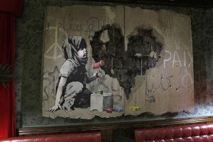 An illustration by street artist Banksy is displayed in his Walled-Off hotel in the Israeli occupied West Bank town of Bethlehem on Dec. 20, 2019. (Credit: AHMAD GHARABLI/AFP via Getty Images)