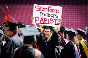 A woman carries a sign in solidarity for a Stanford rape victim during graduation at Stanford University, in Palo Alto, California, on June 12, 2016. Stanford students are protesting the universitys handling of rape cases alledging that the campus keeps secret the names of students found to be responsible for sexual assault and misconduct. (Photo credit should read GABRIELLE LURIE/AFP/Getty Images)