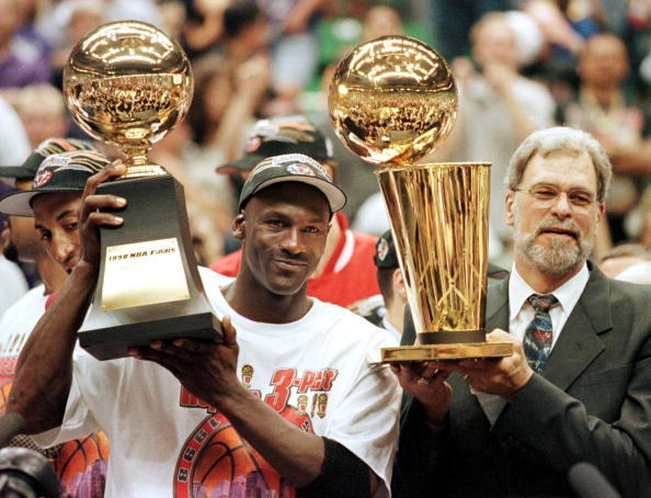 Michael Jordan (L) and Chicago Bulls head coach Phil Jackson (R) Most Valuable Player trophy (L) and the Larry O'Brian trophy (R) 14 June after winning game six of the NBA Finals with the Utah Jazz at the Delta Center in Salt Lake City, UT. The Bulls won the game 87-86 to take their sixth NBA championship. AFP PHOTO Jeff HAYNES (Photo credit should read JEFF HAYNES/AFP/Getty Images)