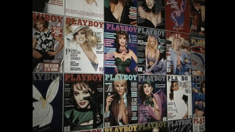 Several covers of Playboy magazine on a wall.